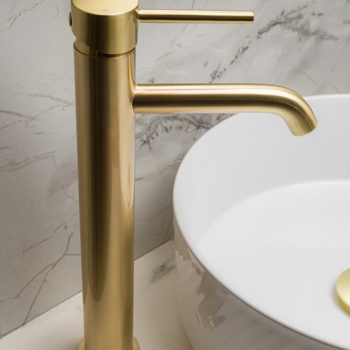 Goldfarbener Wasserhahn über einem eleganten Waschbecken auf Marmoroberfläche.